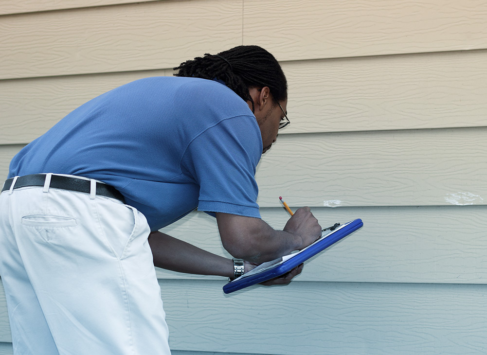 an insurance adjuster looking at siding damage