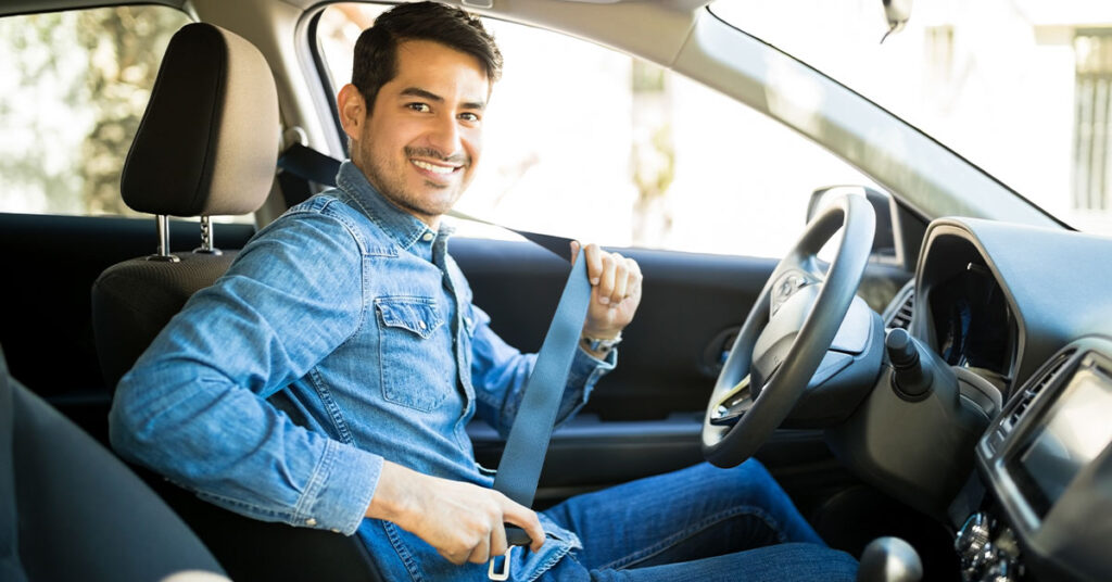 A man smiling while fastening his seatbelt