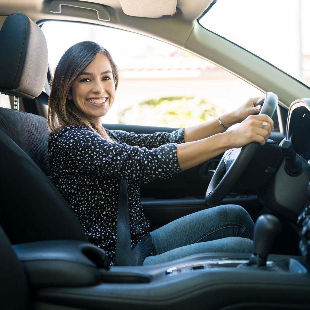 Passenger seat view of a woman smiling while driving