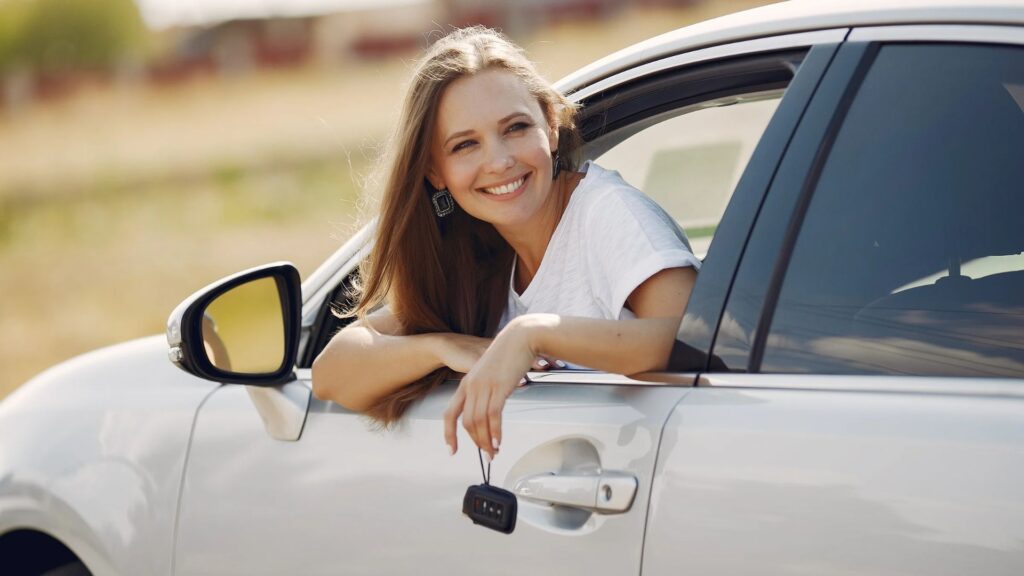 Person smiling while sticking their upper body out of a parked car window