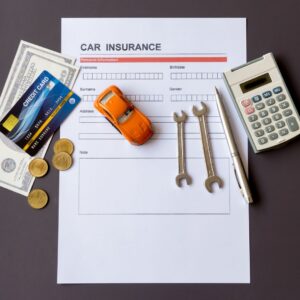 tools and cash on top of car insurance paperwork