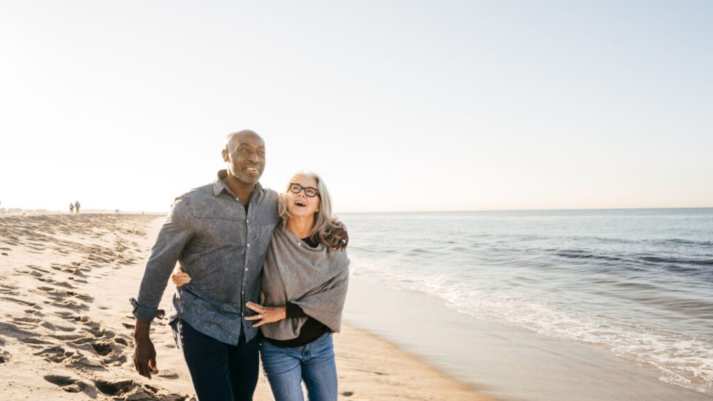 A couple walks together on the beach happily